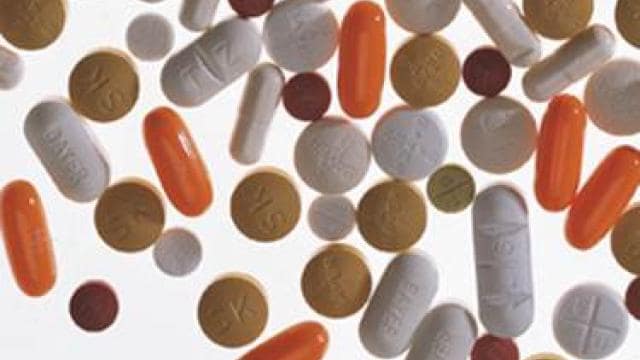 Various pills and capsules scattered on a white background, including white, orange, and brown tablets.