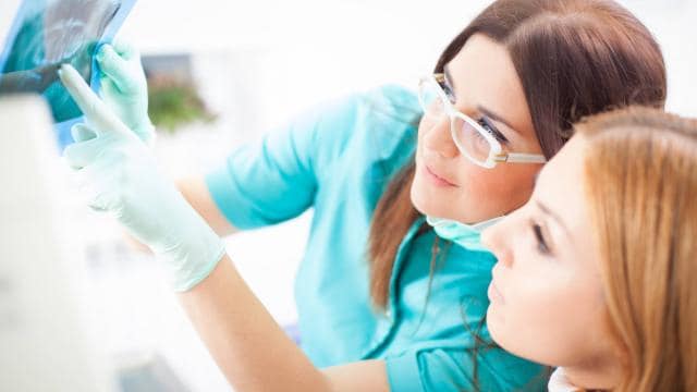 Dentist and patient examining an X-ray image together in a dental office.